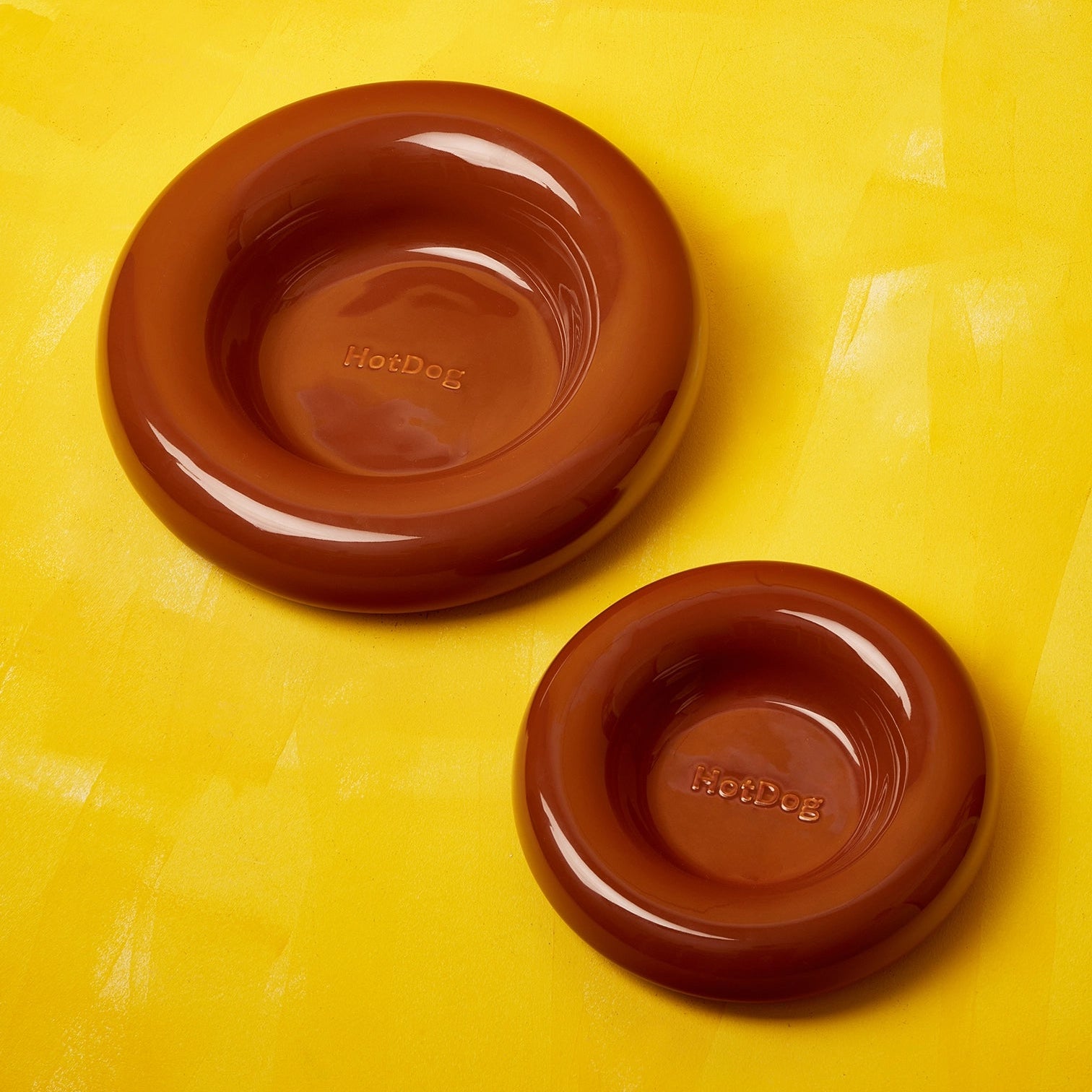Two brown pet bowls on a yellow background