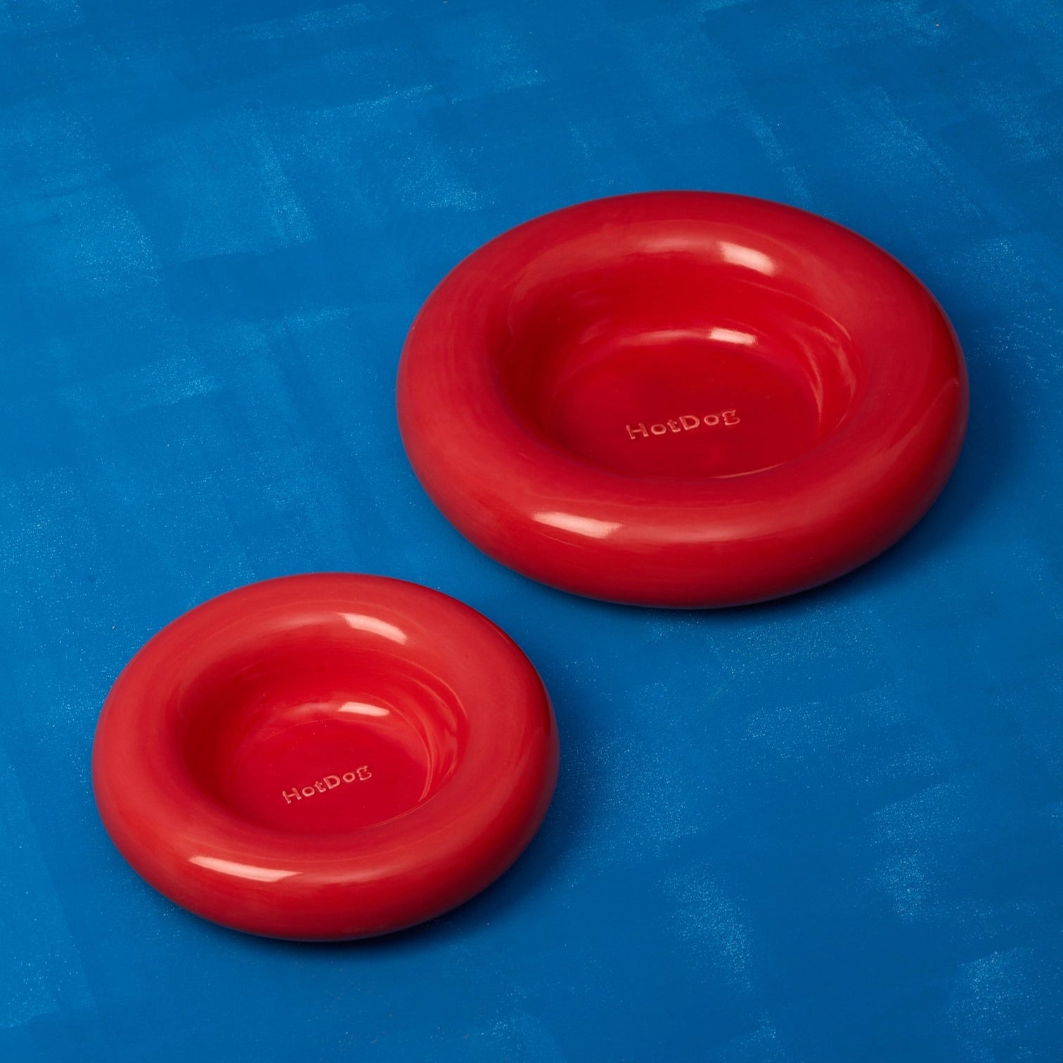 Two red dog bowls with 'HotDog' branding on a blue background