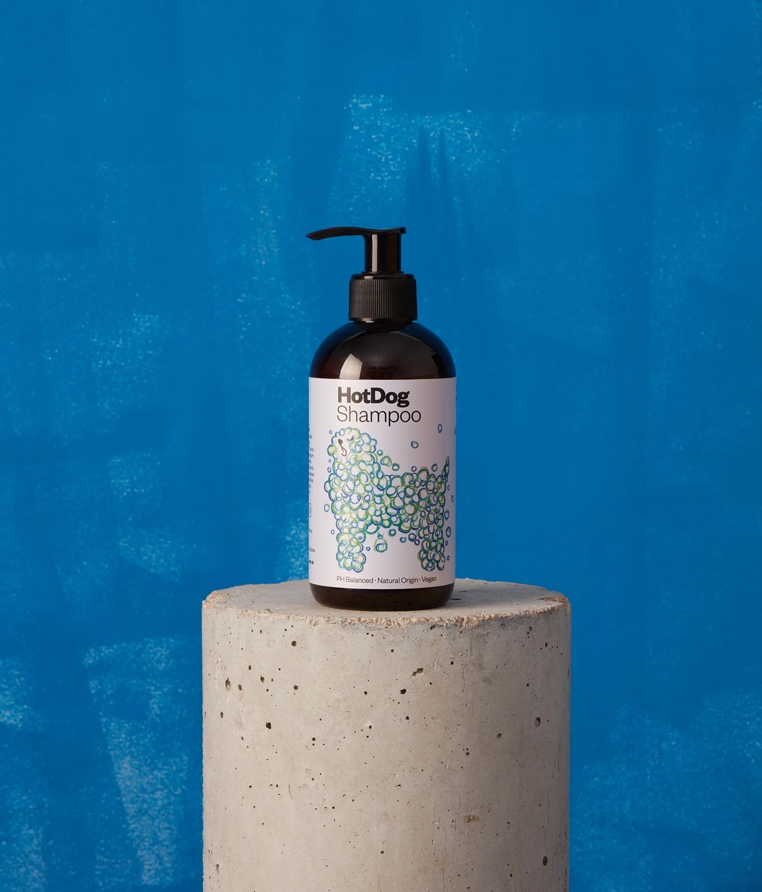 Bottle of HotDog Shampoo on a concrete block with a blue background