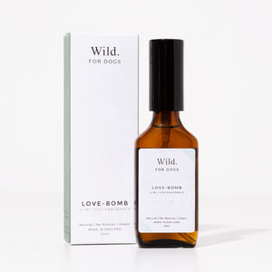 Brown glass bottle of "Love-Bomb" 4-in-1 dog fragrance by Wild for Dogs, next to its box. Made in England, natural, no nasties, vegan. 50ml.