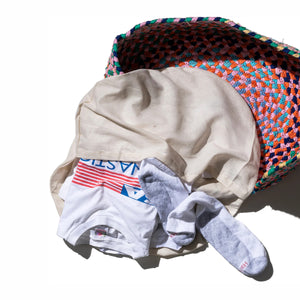 Stack of folded clothes including a shirt, underwear, and socks on a textured surface.