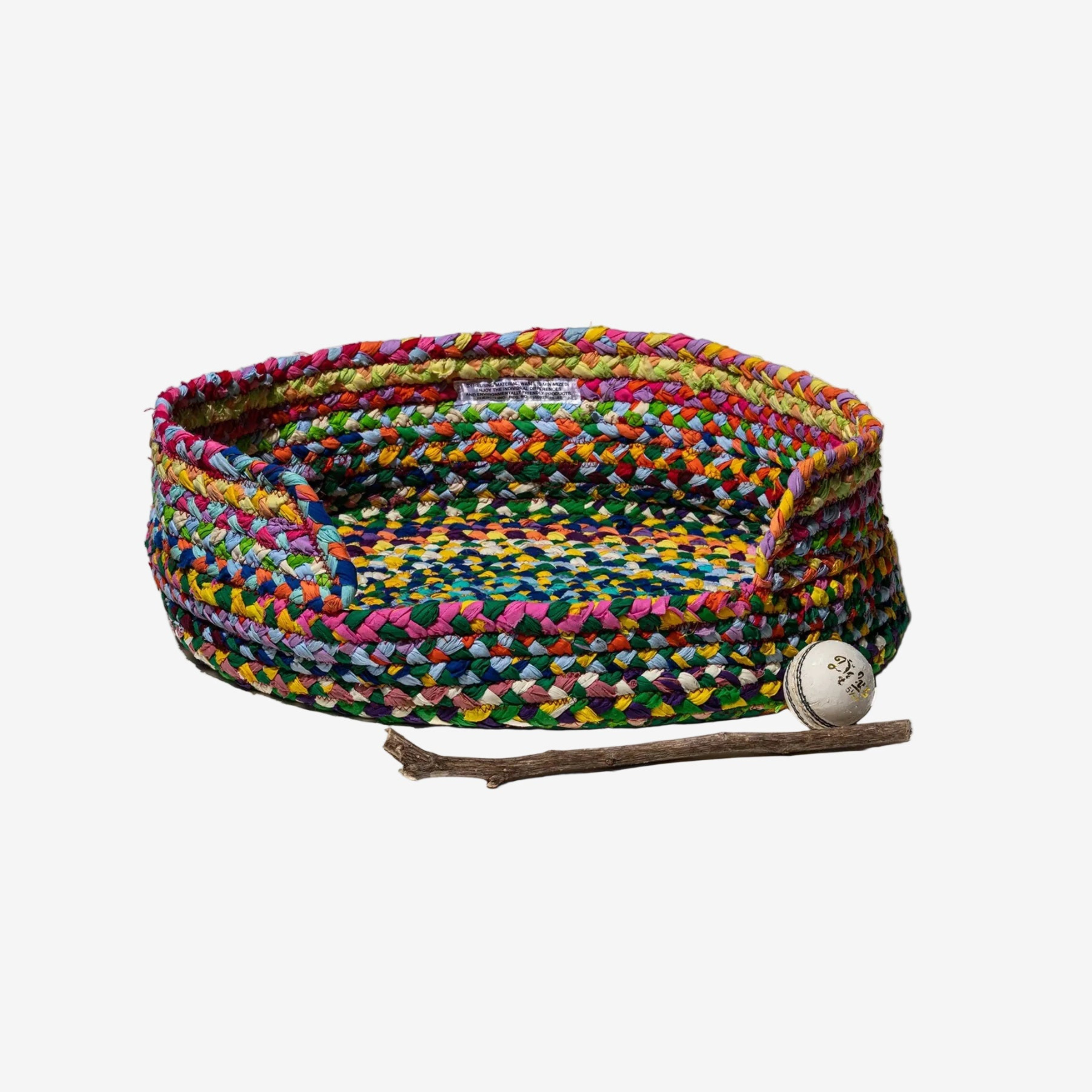 Colorful braided pet bed with a stick and ball on a white background