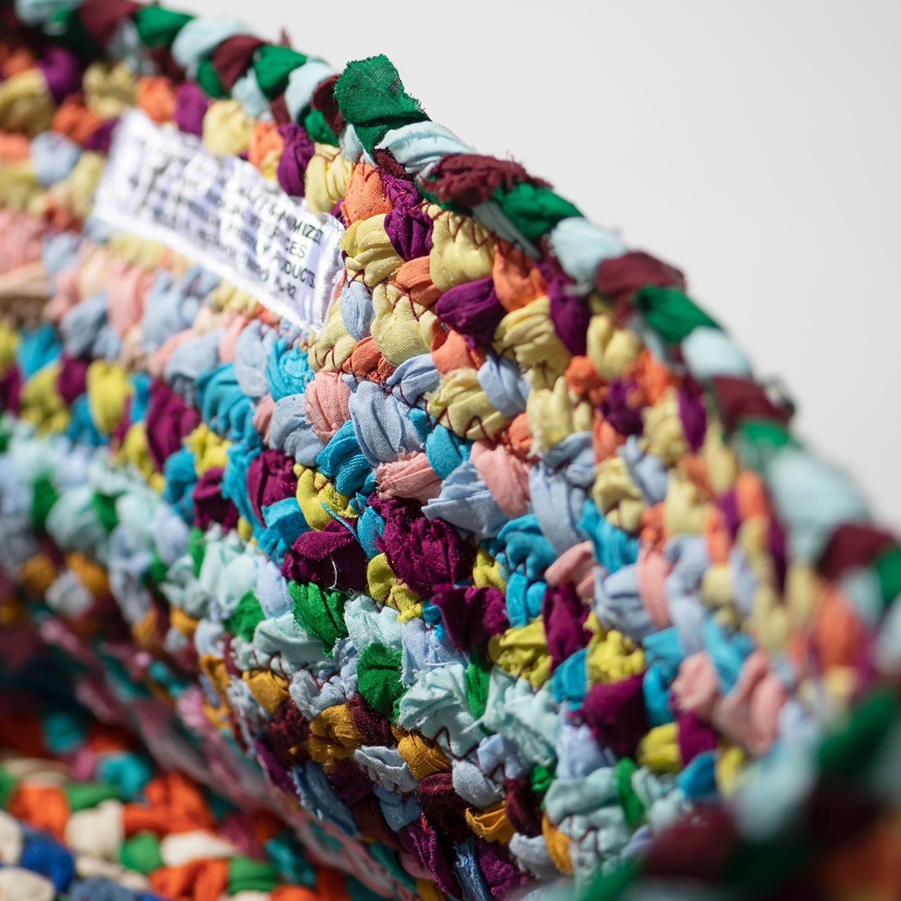 Close-up of a colorful braided rug with a white background