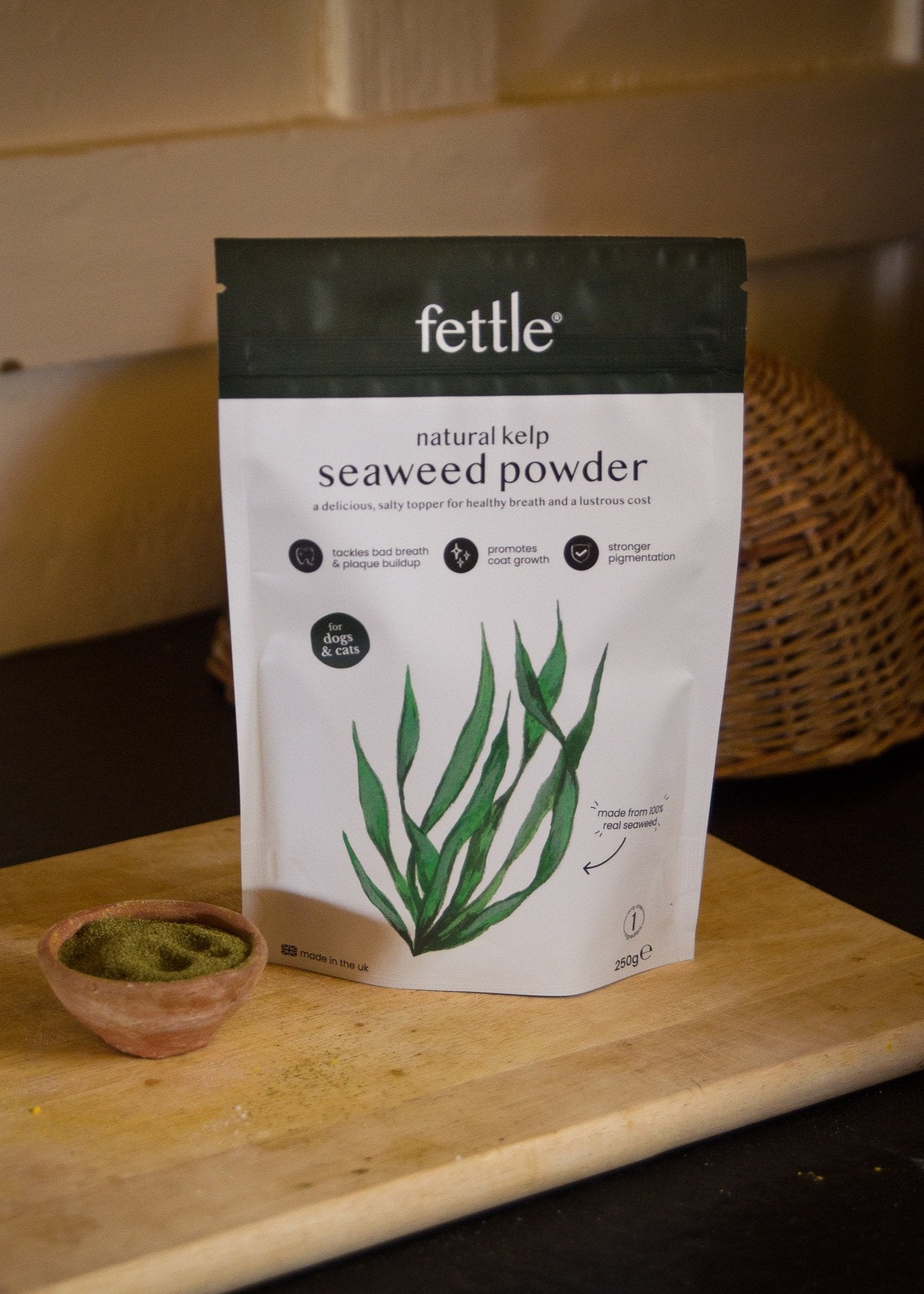 A bag of Fettle natural kelp seaweed powder with a green plant illustration, next to a small bowl of the powder.