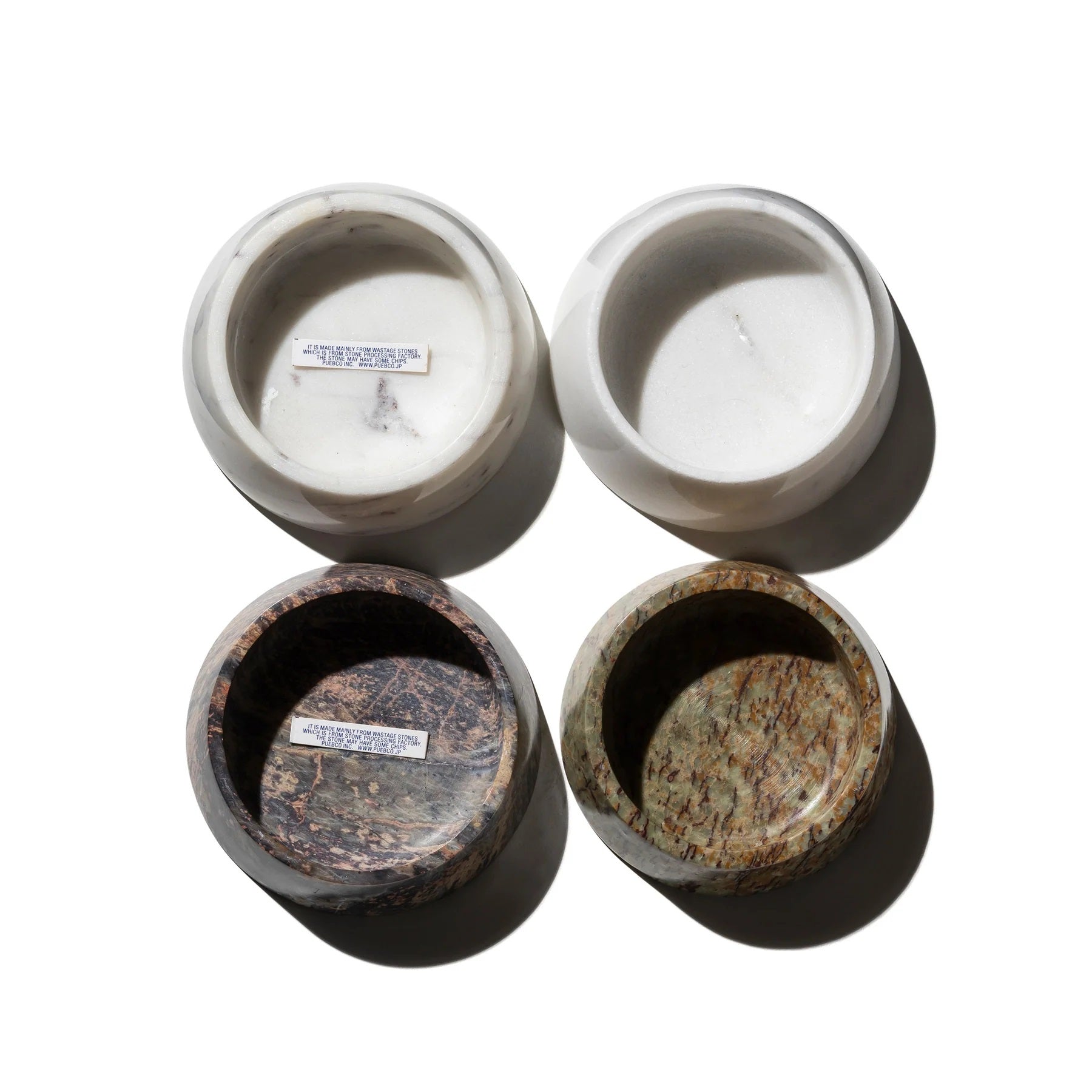 Four stone bowls with different textures and colors on a white background