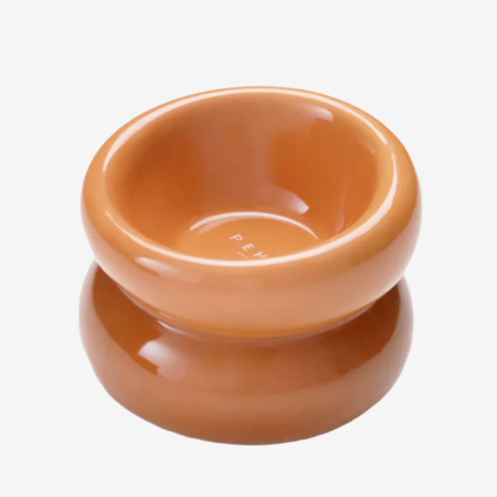 A smooth, glossy terracotta-colored ceramic bowl with a rounded, stacked design against a light background.