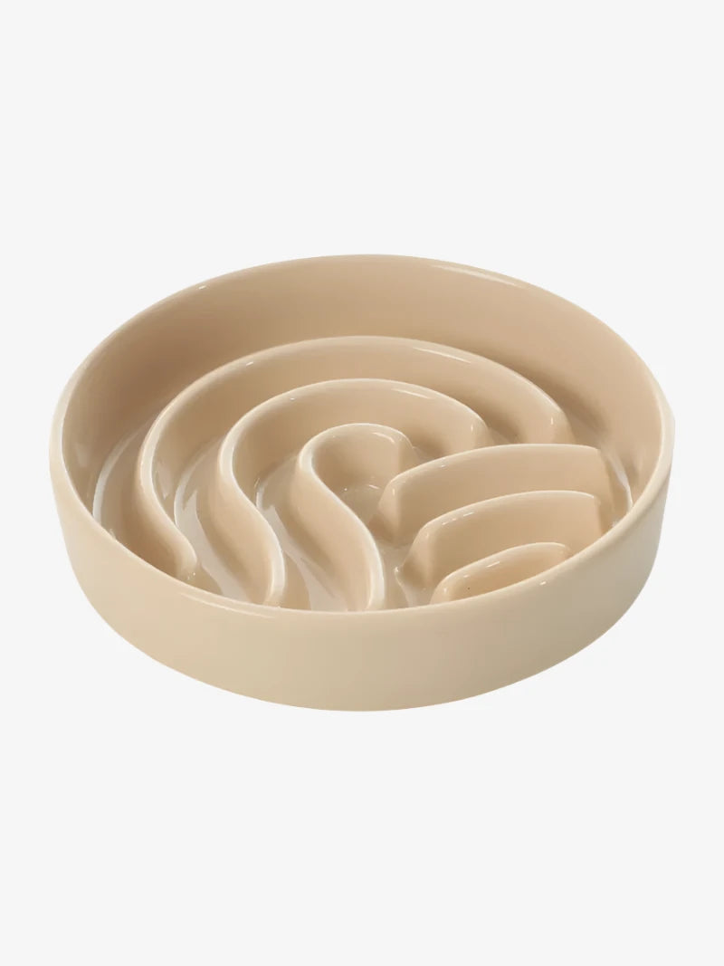 A beige ceramic bowl with a spiral wave design, featuring raised sections for interactive feeding or play.