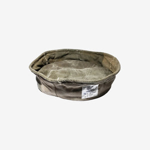 Worn-out military-style dog bed on a white background