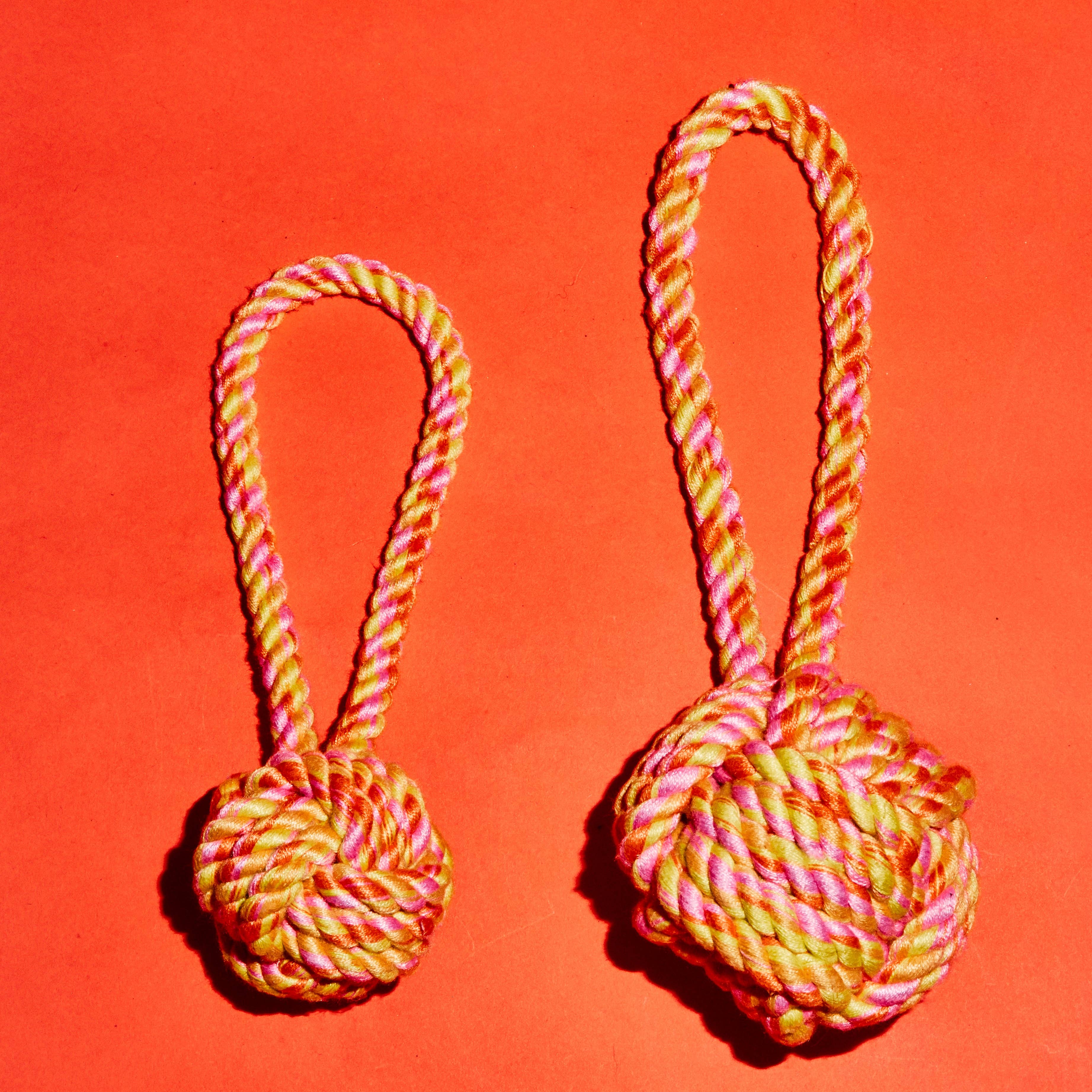 Orange, pink and yellow rope knot toy with loop handle, for dogs to chew and chase in two sizes.