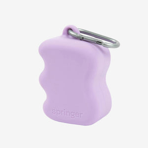 A lilac silicone dog treat dispenser with a wavy design for better grip, featuring a metal carabiner clip for attachment or carrying convenience.