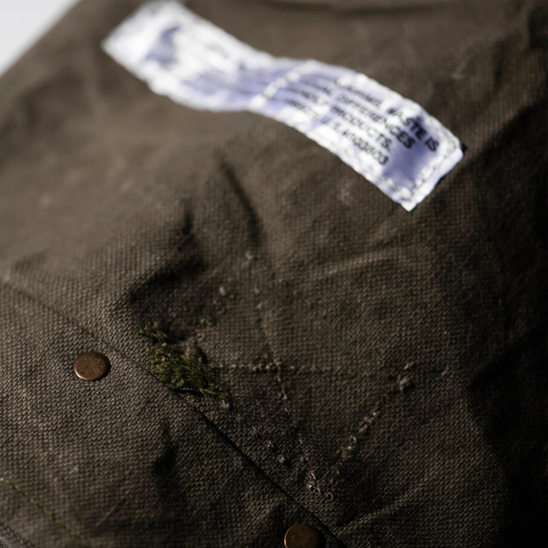 Close-up of a brown dog bed with a label and button, showing signs of wear.