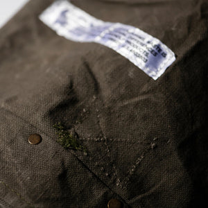 Close-up of a brown dog bed with a label and button, showing signs of wear.
