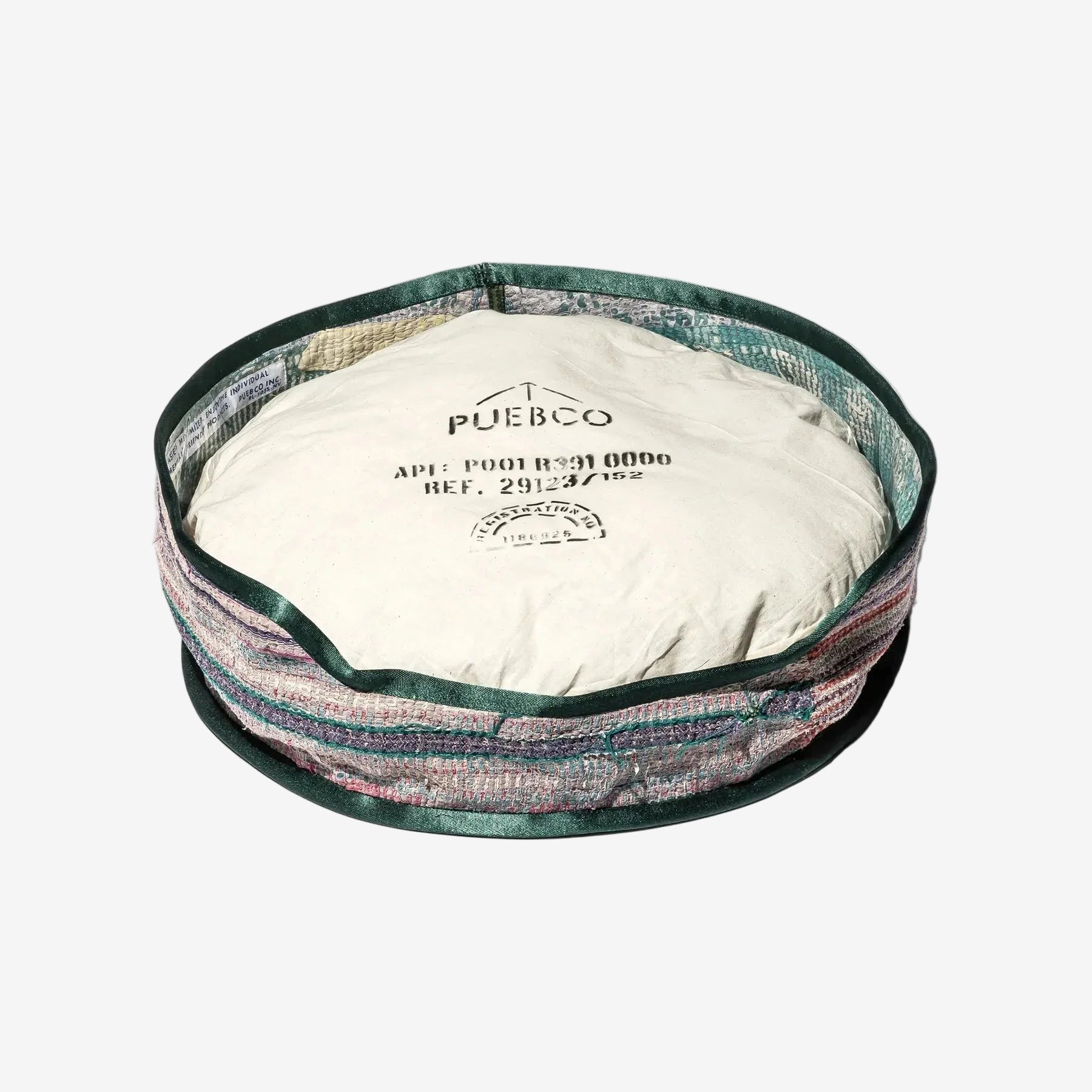 Round pet bed with colorful exterior and white interior, featuring 'Pueblo' branding.