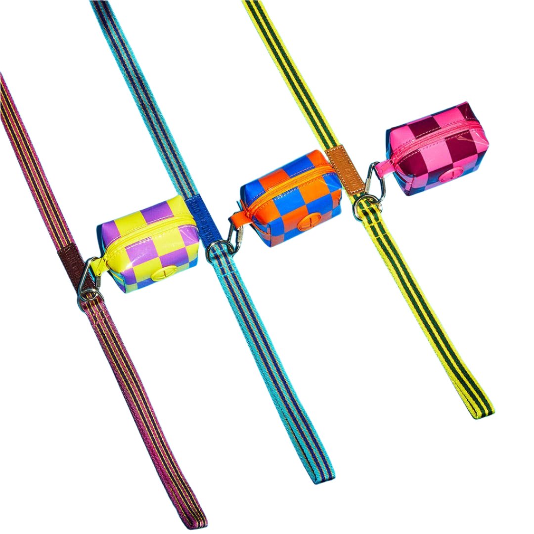 Three small, colourful pouches with striped straps lie in a row, checkered in blue, pink, yellow, and more.